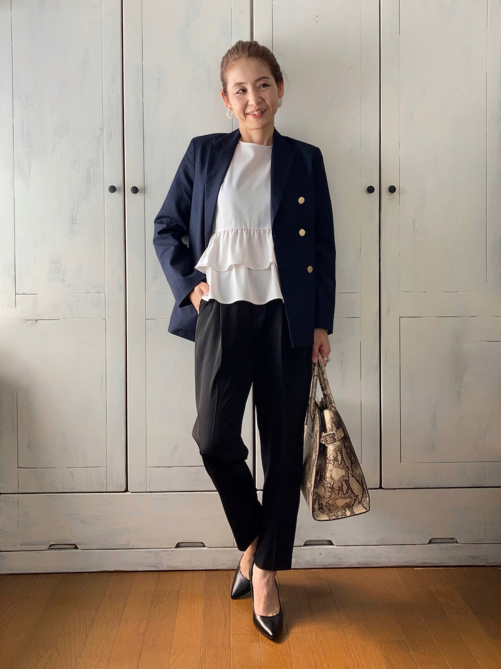 ホワイト系のスーツセット、ブルー系のテーラードジャケット、ベージュ系のバッグを着用したレディースの春コーディネートの3枚目の写真