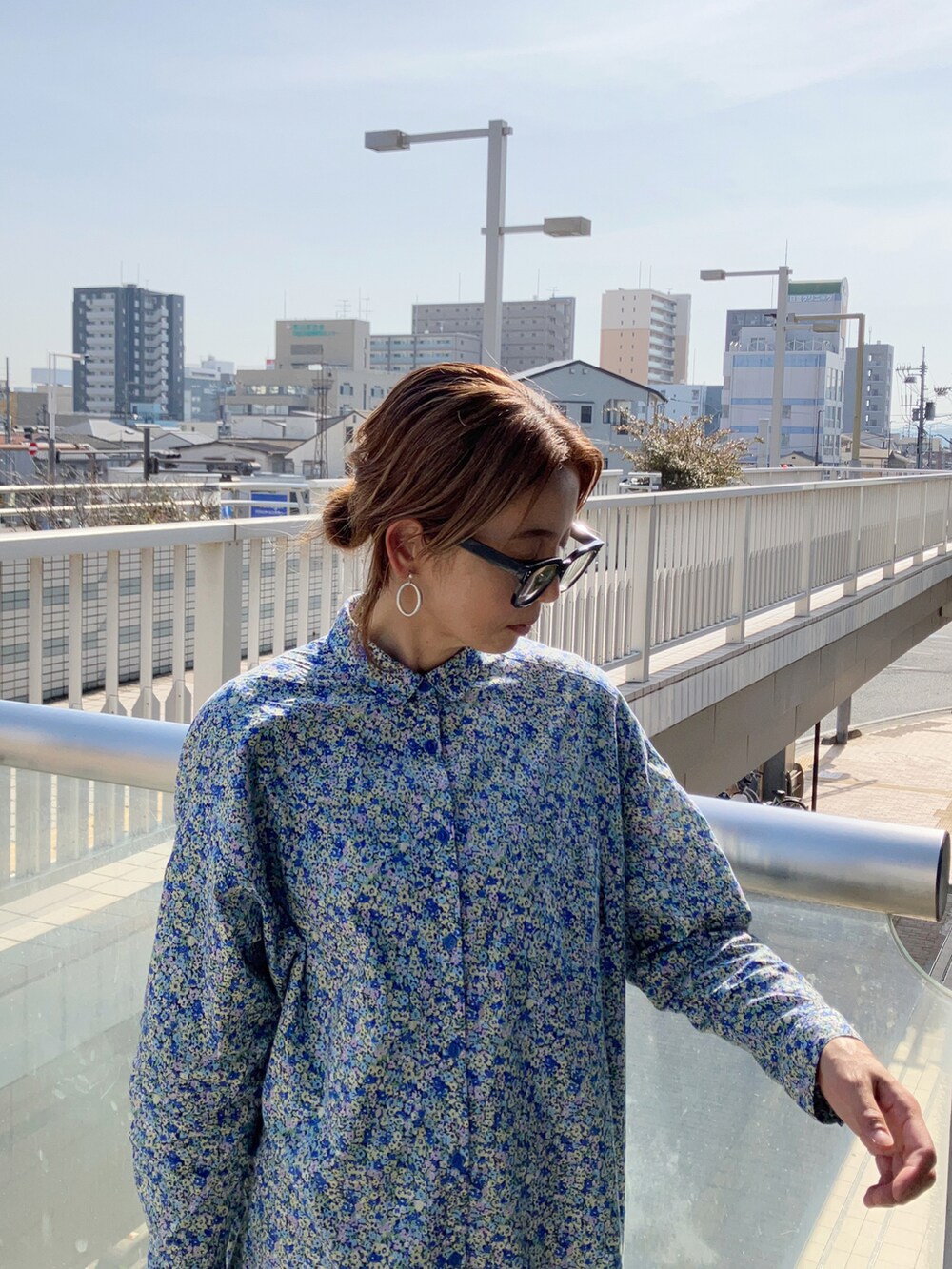 ブルー系のシャツワンピース、ブルー系のパンツ、ブラック系のビジネスバッグを着用したレディースの春コーディネートの2枚目の写真