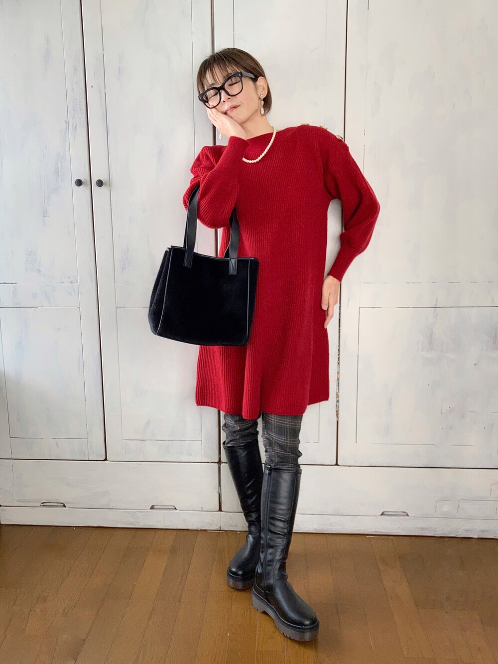 レッド系のワンピース、ブラック系のパンツ、ブラック系のブーツを着用したレディースの冬コーディネートの2枚目の写真