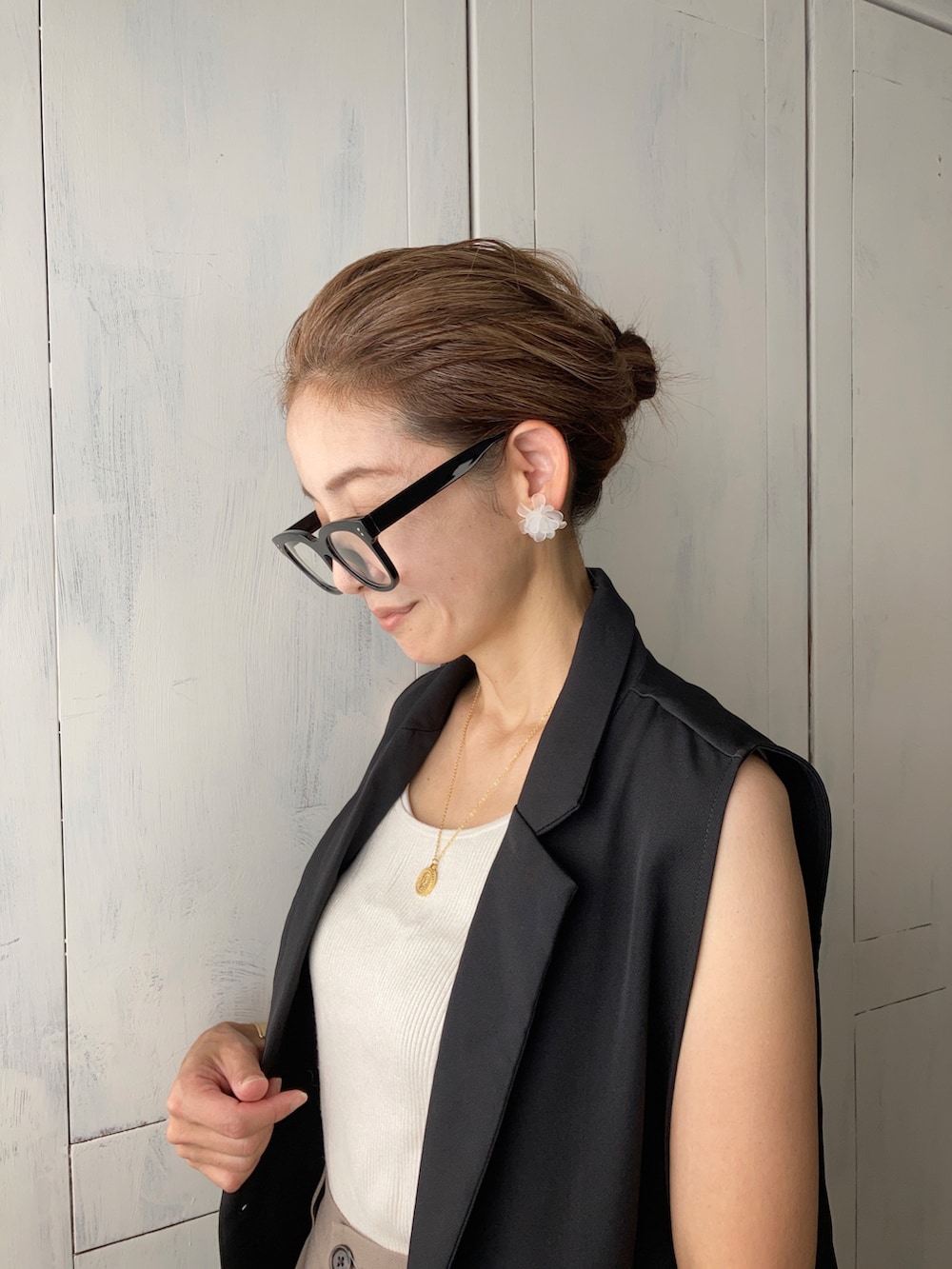 ブラック系のベスト、ベージュ系のパンツ、ベージュ系のかごバッグを着用したレディースの夏コーディネートの3枚目の写真