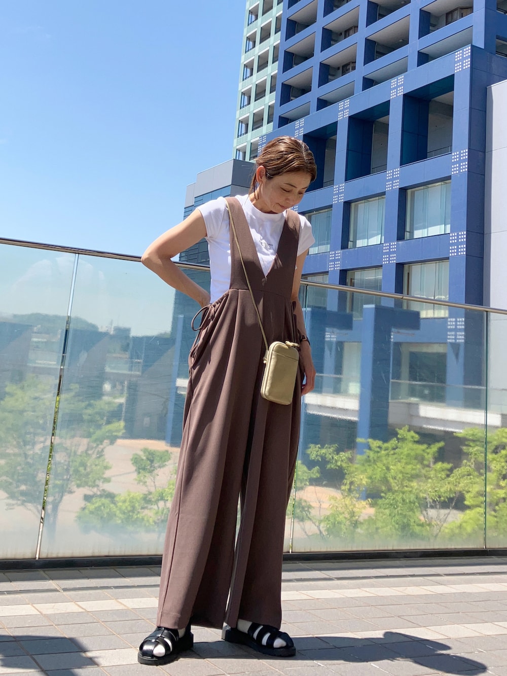 ブラウン系のサロペット/オーバーオール、ホワイト系のTシャツ/カットソー、ゴールド系のバッグを着用したレディースの春コーディネートの3枚目の写真