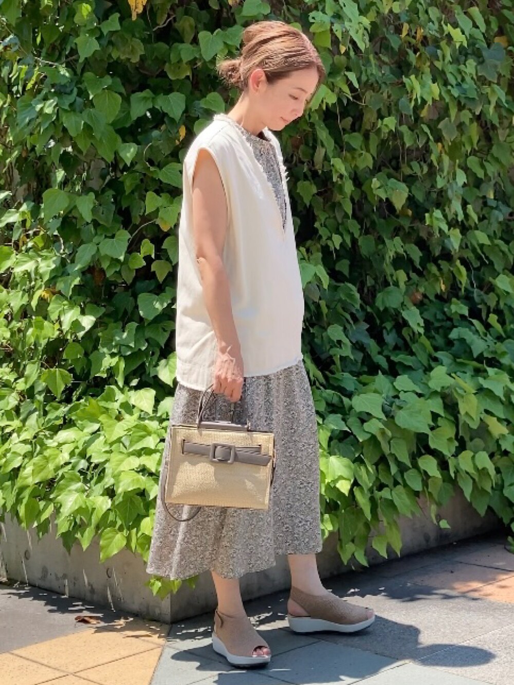 ベージュ系のベスト、グリーン系のワンピース、グレー系のハンドバッグを着用したレディースの夏コーディネートの2枚目の写真