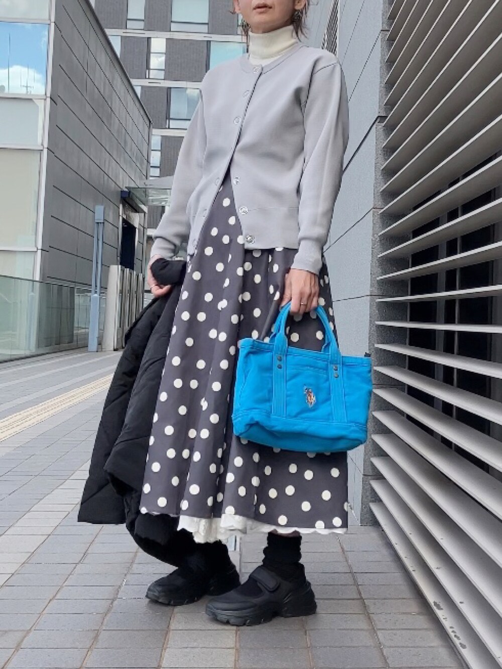 ブラック系のダウンジャケット/コート、グレー系のカーディガン/ボレロ、グレー系のスカートを着用したレディースの冬コーディネートの3枚目の写真