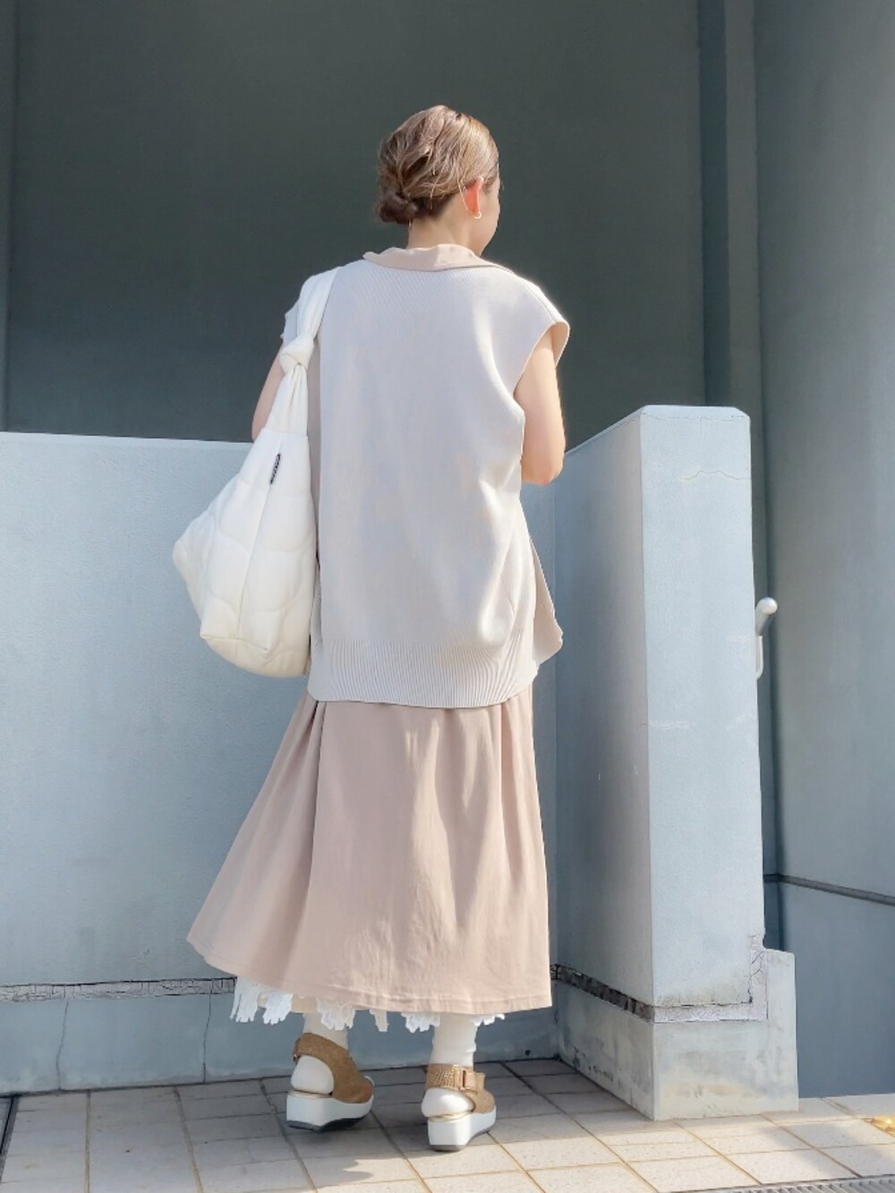 ベージュ系のベスト、ベージュ系のワンピース、ホワイト系のショルダーバッグを着用したレディースの夏コーディネートの3枚目の写真