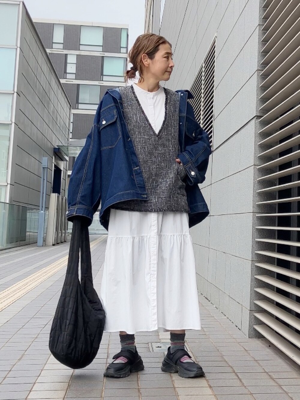 グレー系のベスト、ブルー系のデニムジャケット、ホワイト系のワンピース/ドレスを着用したレディースの春コーディネートの4枚目の写真