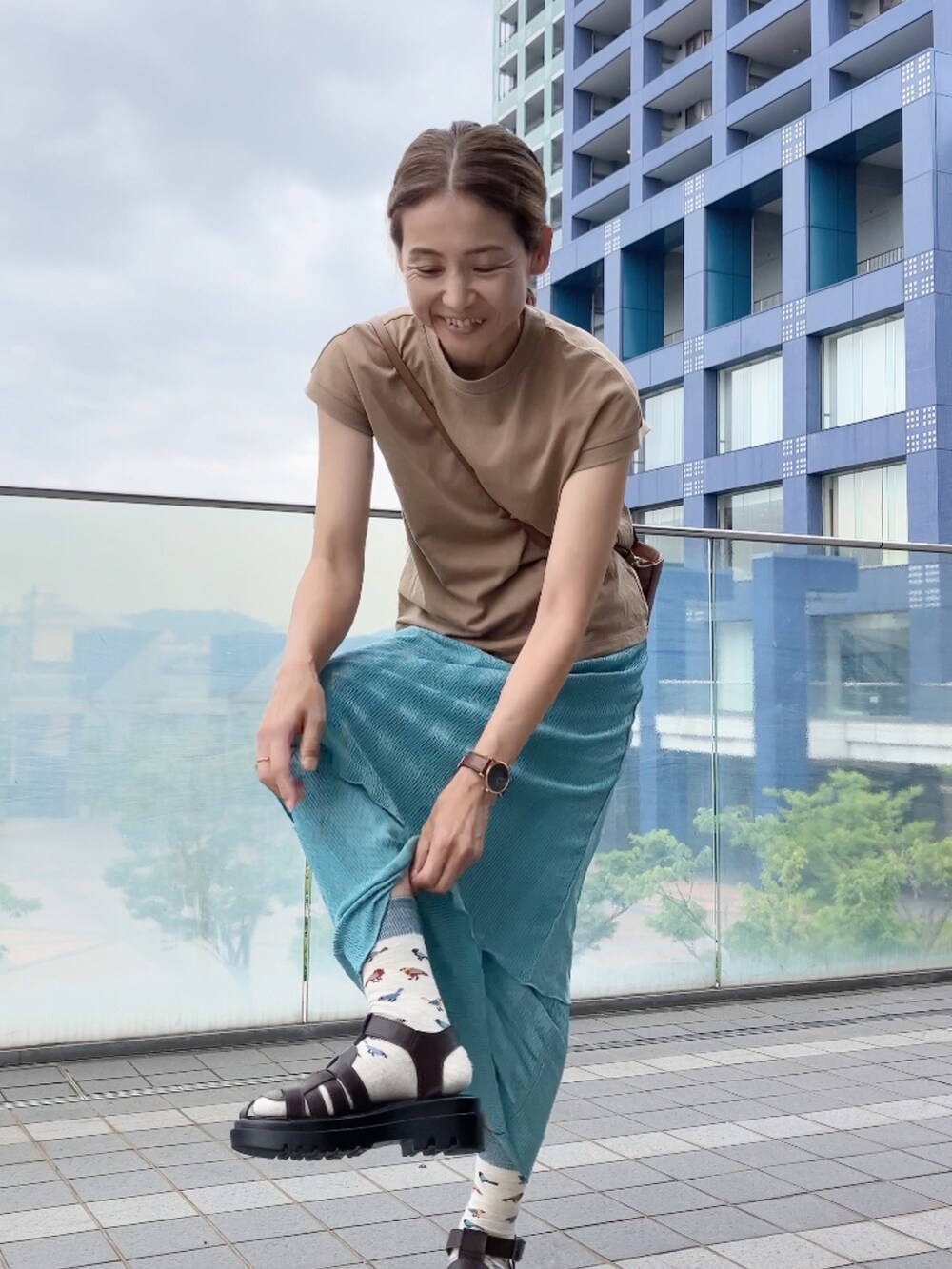 ブルー系のスカート、ベージュ系のTシャツ/カットソー、ブラウン系のサンダルを着用したレディースの夏コーディネートの2枚目の写真