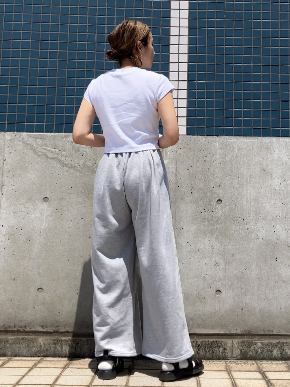 ホワイト系のTシャツ/カットソー、グレー系のスウェットパンツ、ブラック系のサンダルを着用したレディースの春コーディネートの3枚目の写真