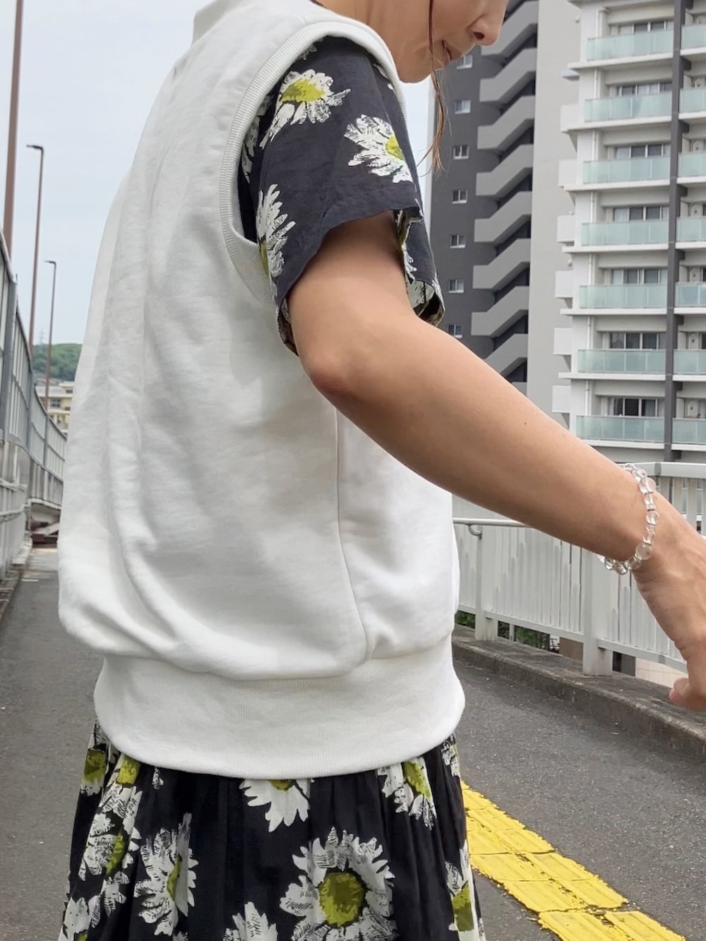 ホワイト系のベスト、ブラック系のワンピース、ブラック系のサンダルを着用したレディースの春コーディネートの2枚目の写真