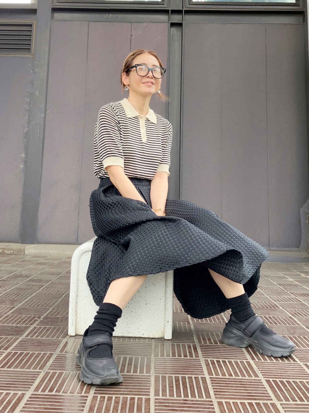 ブラック系のトップス、ブラック系のスカート、ブラック系のビジネスバッグを着用したレディースの春コーディネートの2枚目の写真