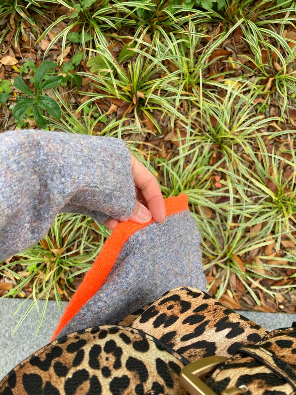 グレー系のニット/セーター、ブラック系のダウンジャケット/コート、オレンジ系のスカートを着用したレディースの冬コーディネートの4枚目の写真