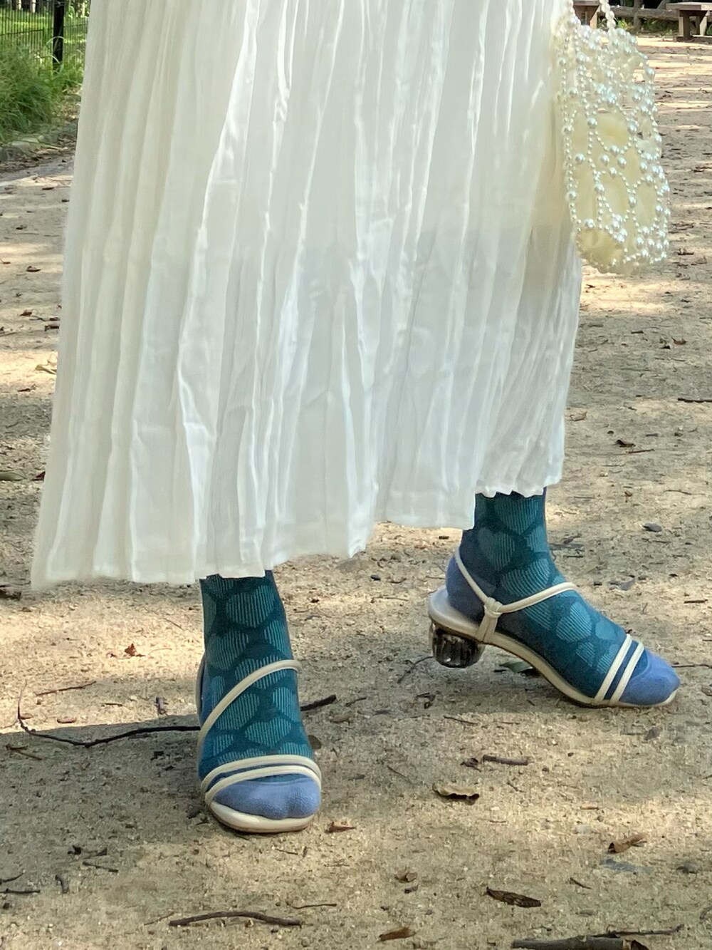 ホワイト系のワンピース、グリーン系のニット/セーター、ホワイト系のハンドバッグを着用したレディースの夏コーディネートの2枚目の写真