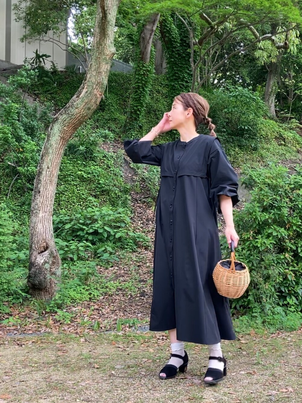 ブラック系のシャツワンピース、ブラック系のサンダル、ベージュ系のかごバッグを着用したレディースの春コーディネートの2枚目の写真