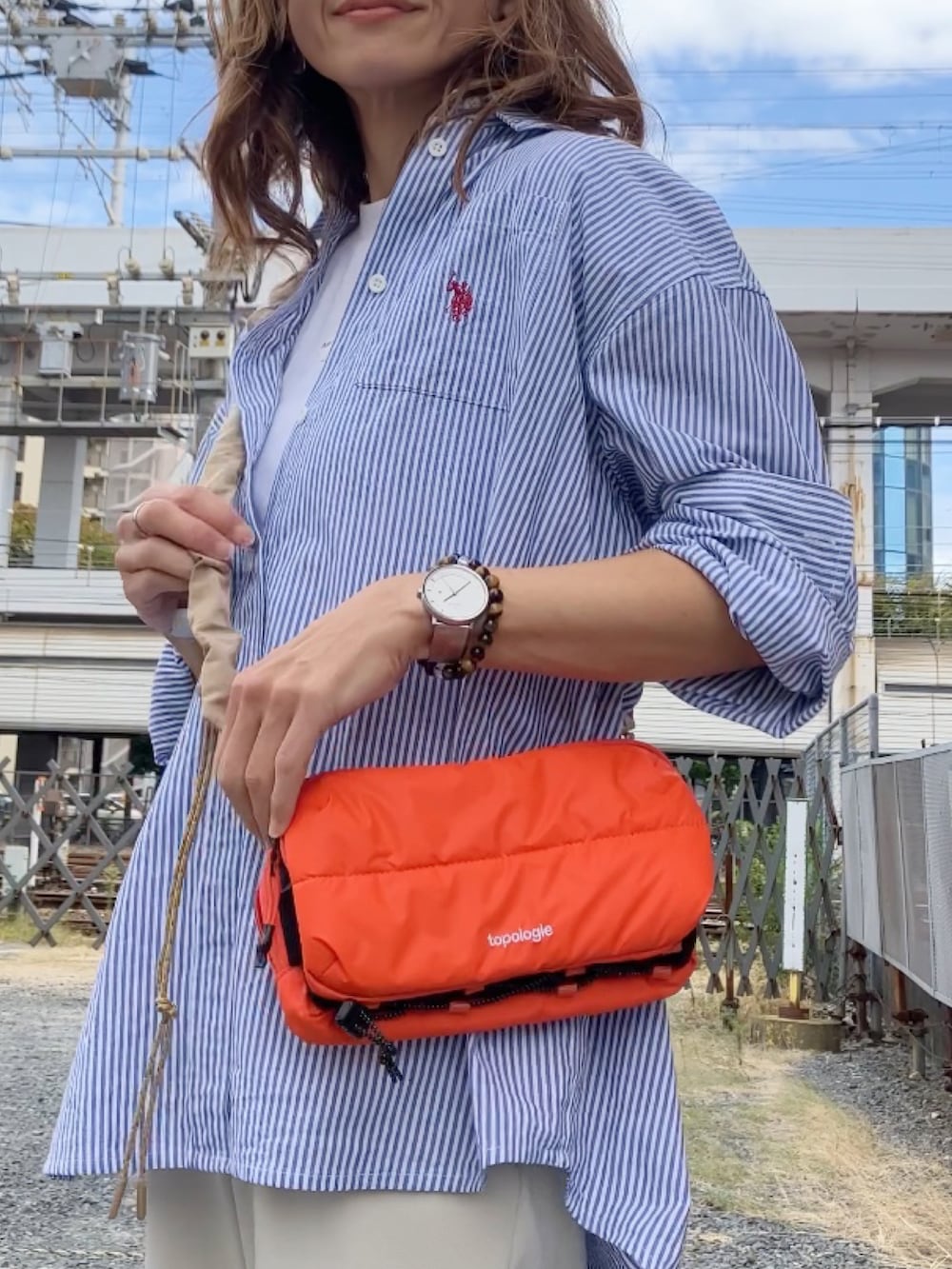 オレンジ系のショルダーバッグ、ブルー系のシャツ/ブラウス、ホワイト系のパンツを着用したレディースの秋コーディネートの3枚目の写真