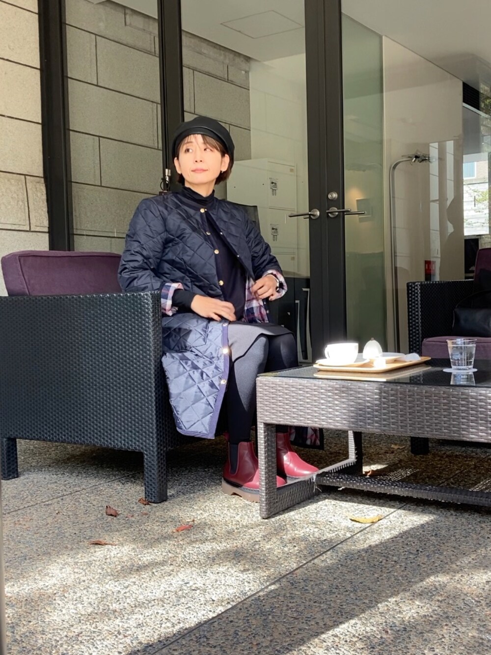 ブルー系のノーカラーコート、グレー系のワンピース、ブラック系のスーツセットを着用したレディースの秋コーディネートの4枚目の写真