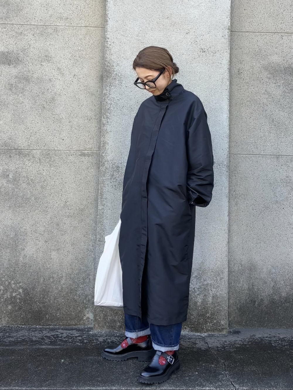 ブラック系のシューズ、ブラック系のステンカラーコート、ホワイト系のエコバッグ/サブバッグを着用したレディースの秋コーディネートの3枚目の写真