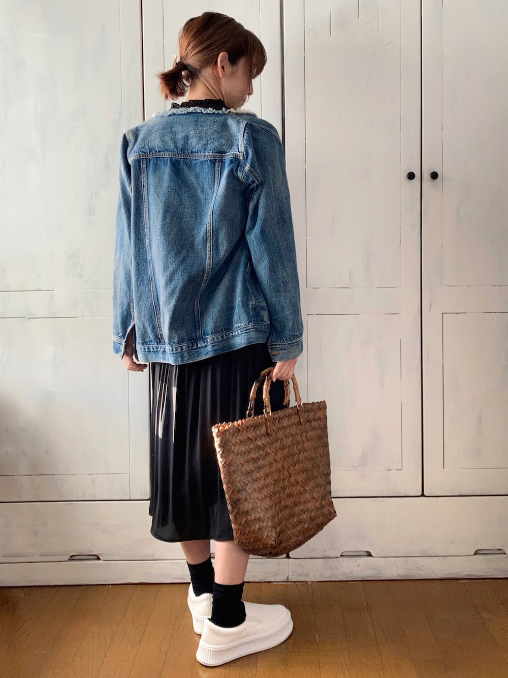 ブラック系のワンピース、ブルー系のデニムジャケット、ブラウン系のかごバッグを着用したレディースの冬コーディネートの2枚目の写真