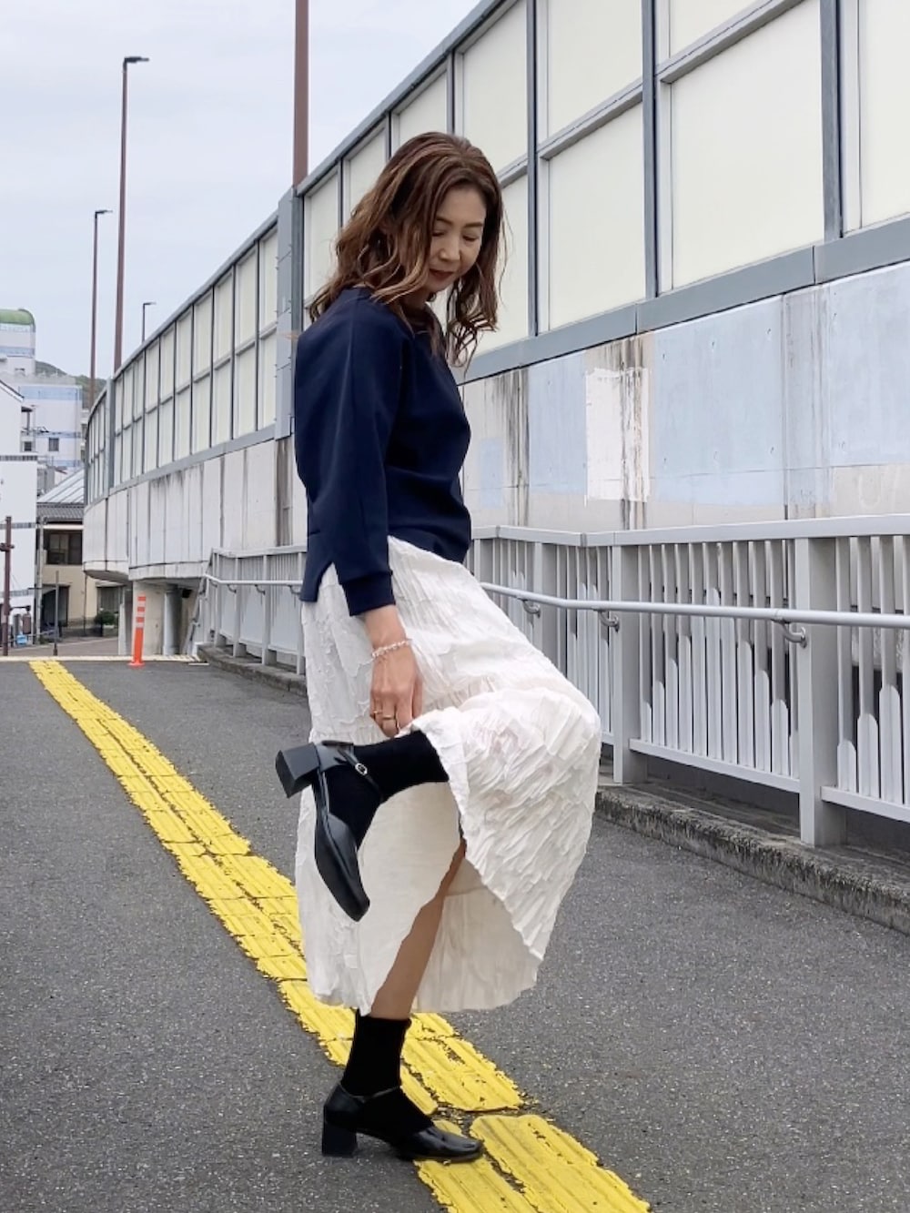 ブルー系のトップス、ブラック系のパンプス、イエロー系のバックパック/リュックを着用したレディースの春コーディネートの3枚目の写真