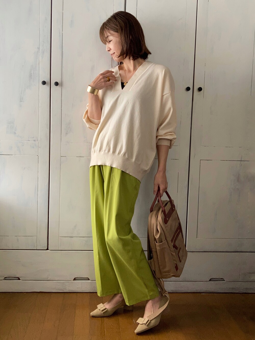 グリーン系のテーラードジャケット、ホワイト系のニット/セーター、ベージュ系のバックパック/リュックを着用したレディースの春コーディネートの2枚目の写真