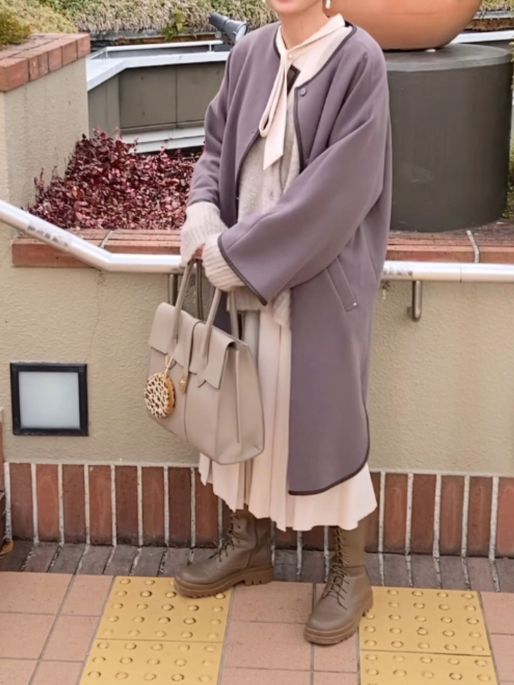 ベージュ系のワンピース、ベージュ系のカーディガン/ボレロ、ベージュ系のビジネスバッグを着用したレディースの冬コーディネートの3枚目の写真