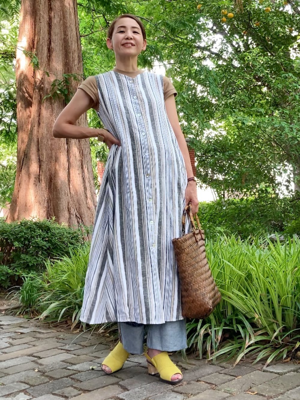 ホワイト系のワンピース、ブルー系のデニムパンツ、イエロー系のサンダルを着用したレディースの夏コーディネートの2枚目の写真