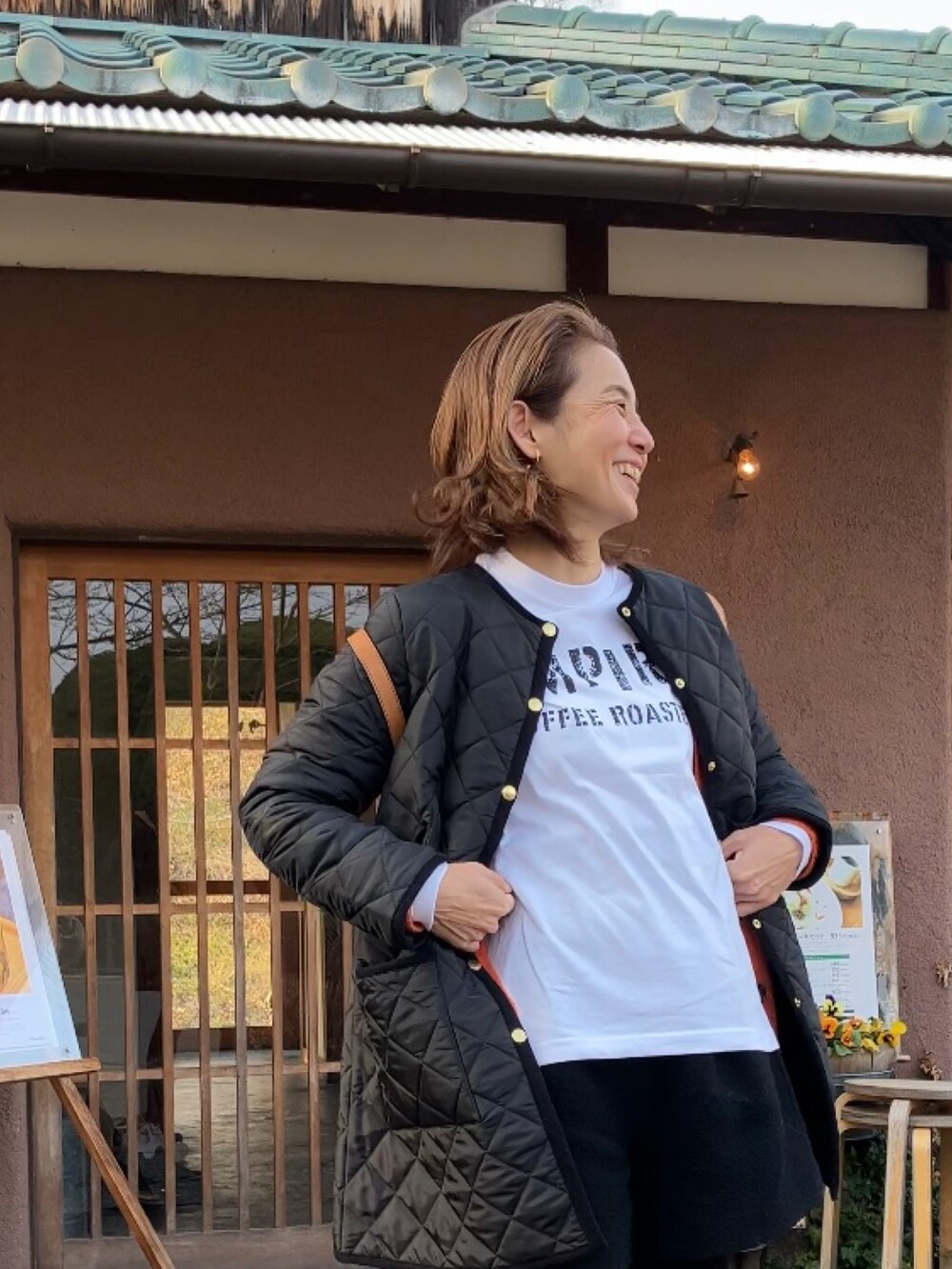 ホワイト系のTシャツ/カットソー、オレンジ系のカーディガン/ボレロ、ブラック系のその他アウターを着用したレディースの冬コーディネートの4枚目の写真