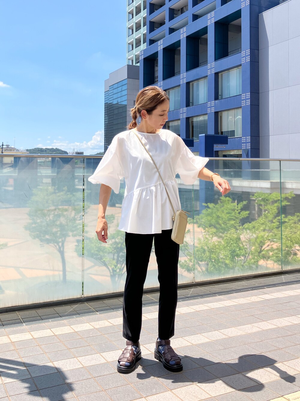 ホワイト系のシャツ/ブラウス、ブラック系のパンツ、ゴールド系のバッグを着用したレディースの夏コーディネートの2枚目の写真