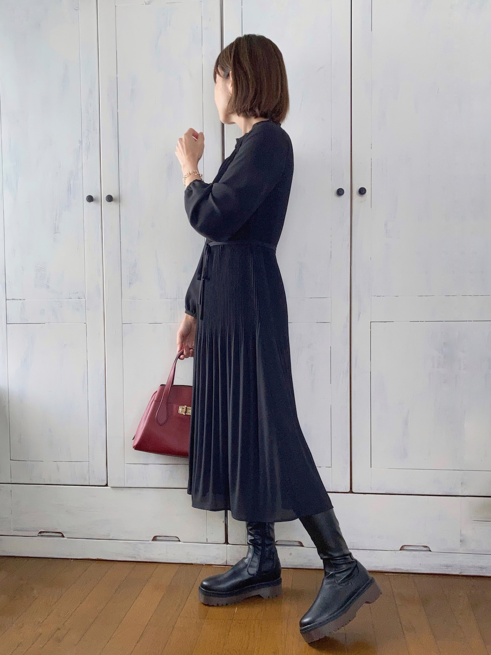 ブラック系のワンピース、ブラック系のハンドバッグ、ブラック系のブーツを着用したレディースの冬コーディネートの2枚目の写真