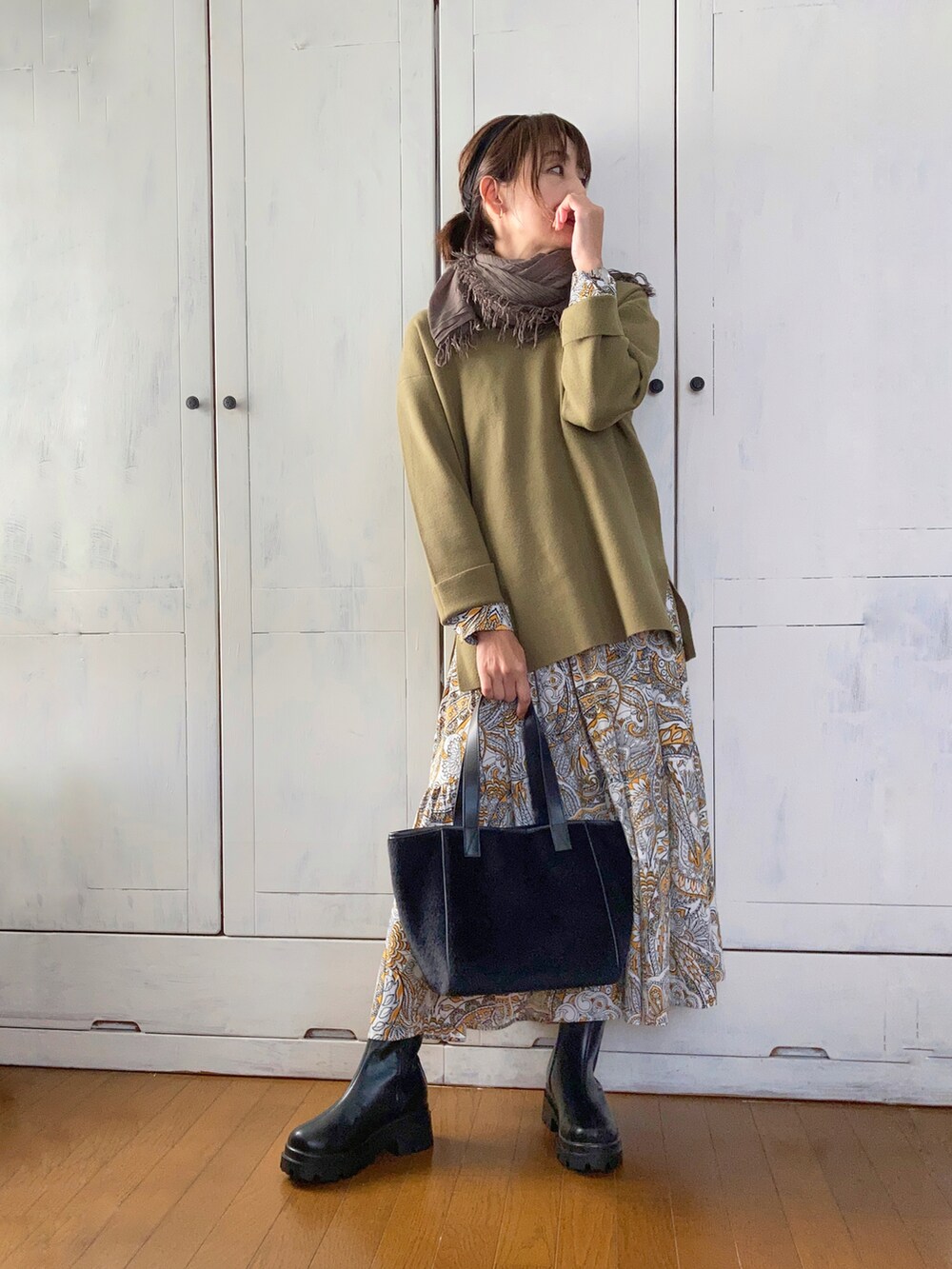 グリーン系のニット/セーター、イエロー系のワンピース、ブラック系のブーツを着用したレディースの秋コーディネートの3枚目の写真