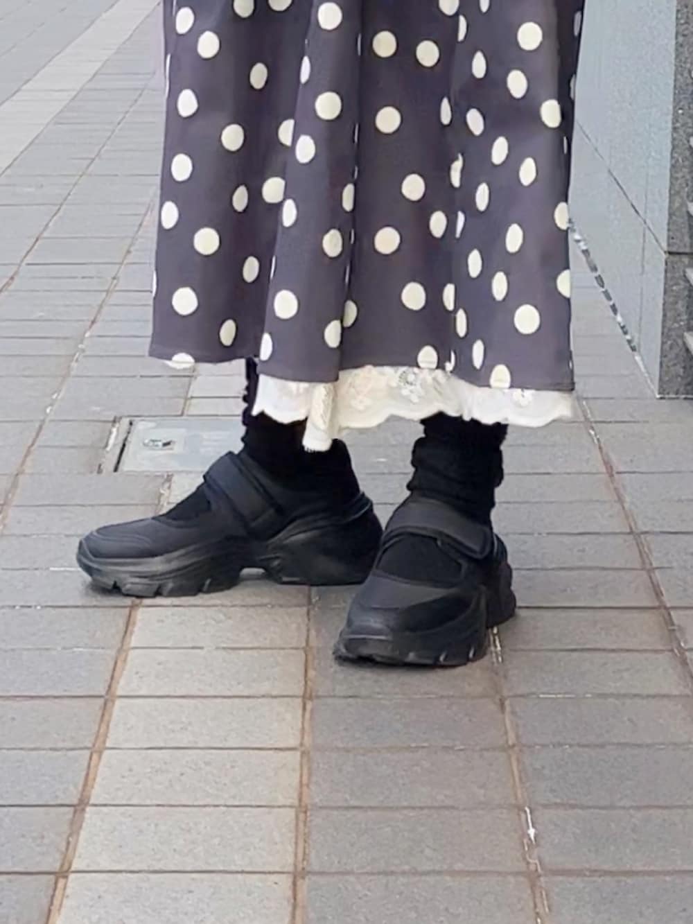 ブラック系のダウンジャケット/コート、グレー系のカーディガン/ボレロ、グレー系のスカートを着用したレディースの冬コーディネートの2枚目の写真