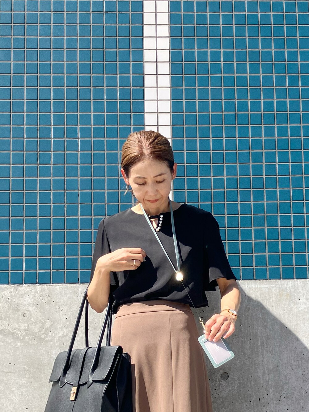 ブラック系のシャツ/ブラウス、ブラウン系のスカート、ブラック系のビジネスバッグを着用したレディースの夏コーディネートの3枚目の写真