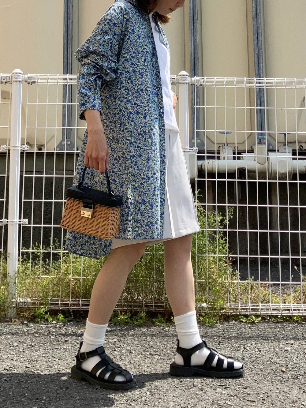 ブルー系のシャツワンピース、ブラウン系のかごバッグ、ブラック系のサンダルを着用したレディースの春コーディネートの3枚目の写真