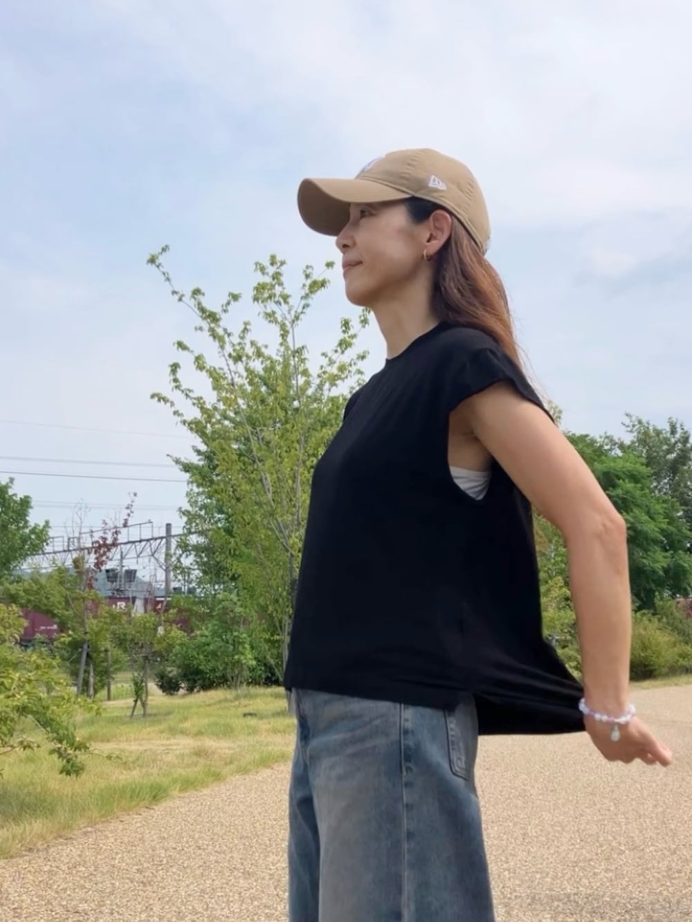 ブラック系のTシャツ/カットソー、ブラウン系のバッグ、ベージュ系のキャップを着用したレディースの夏コーディネートの2枚目の写真