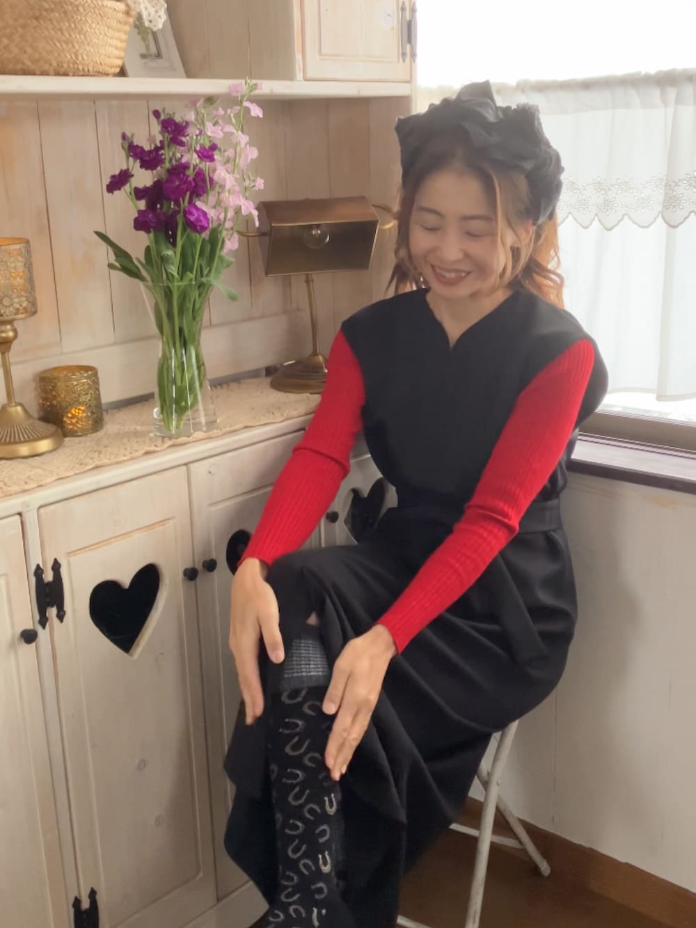 ブラック系のジャンパースカート、ブラック系のレッグウェア、ブラック系のヘアバンドを着用したレディースの冬コーディネートの2枚目の写真