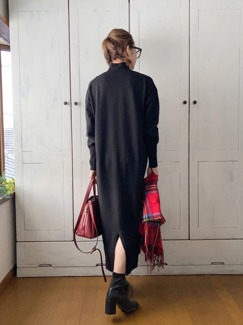 ブラック系のワンピース、レッド系のハンドバッグ、ブラック系のブーツを着用したレディースの秋コーディネートの2枚目の写真