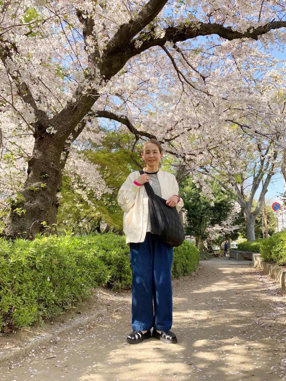 ホワイト系のMA-1、ブラック系のTシャツ/カットソー、ブルー系のデニムパンツを着用したレディースの春コーディネートの3枚目の写真