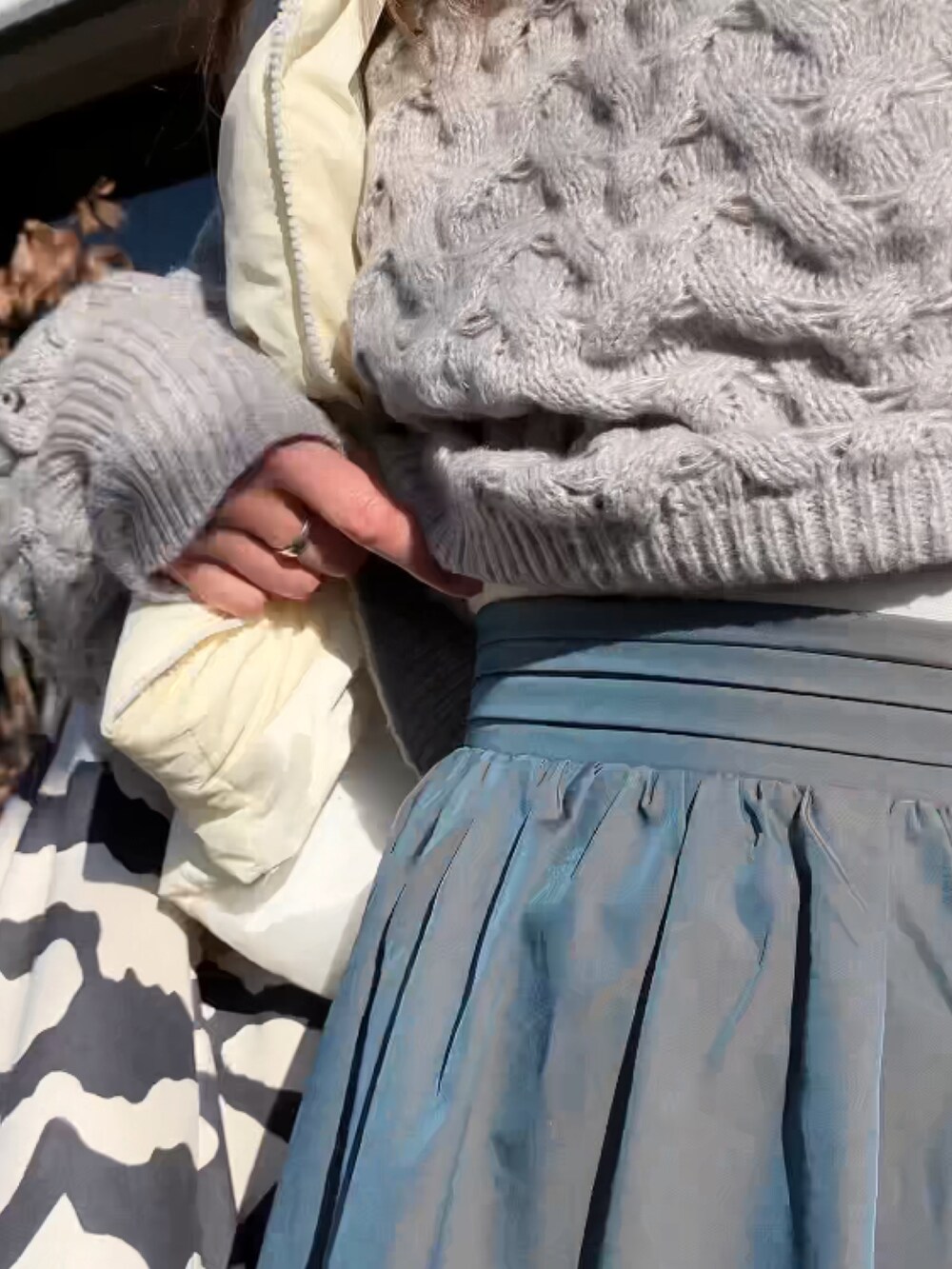 ベージュ系のニット/セーター、グリーン系のスカート、ホワイト系のダウンベストを着用したレディースの冬コーディネートの2枚目の写真