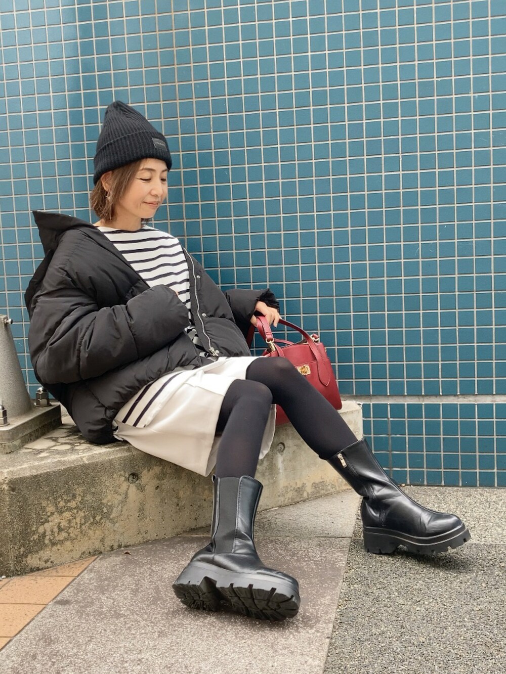 ブルー系のTシャツ/カットソー、ブラック系のダウンジャケット/コート、ベージュ系のその他パンツを着用したレディースの秋コーディネートの2枚目の写真