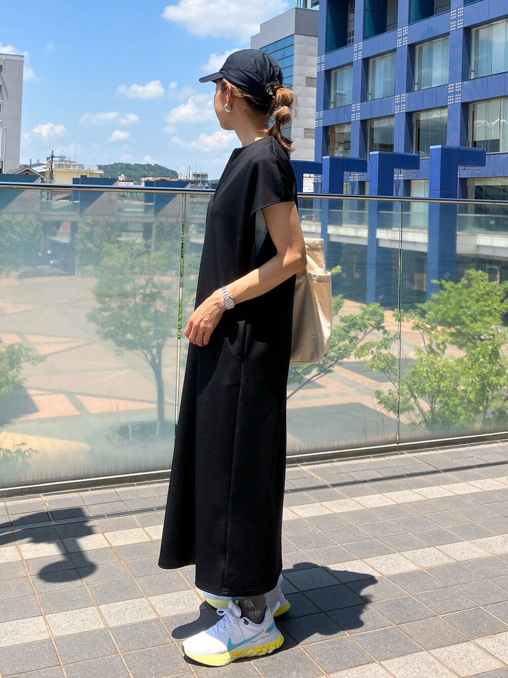 ブラック系のワンピース、ブルー系のTシャツ/カットソー、ホワイト系のスニーカーを着用したレディースの夏コーディネートの2枚目の写真