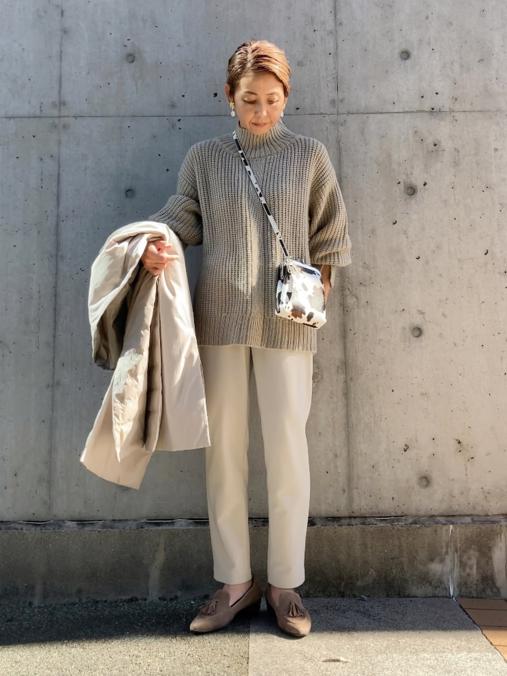 ホワイト系のパンツ、ベージュ系のニット/セーター、ベージュ系のシューズを着用したレディースの秋コーディネートの3枚目の写真