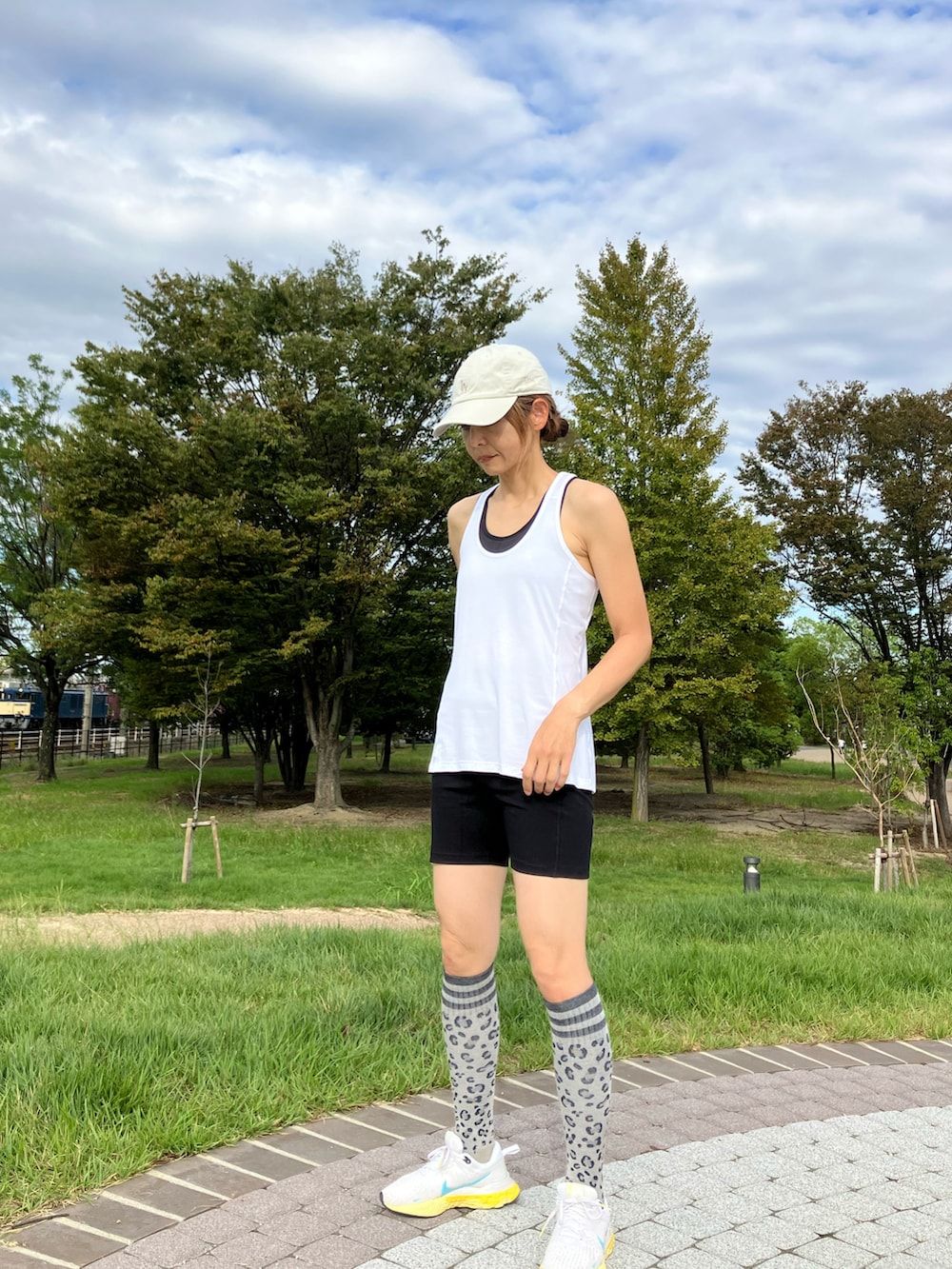 ホワイト系のタンクトップ、ホワイト系のスニーカー、ブラック系のレギンス/スパッツを着用したレディースの秋コーディネートの3枚目の写真