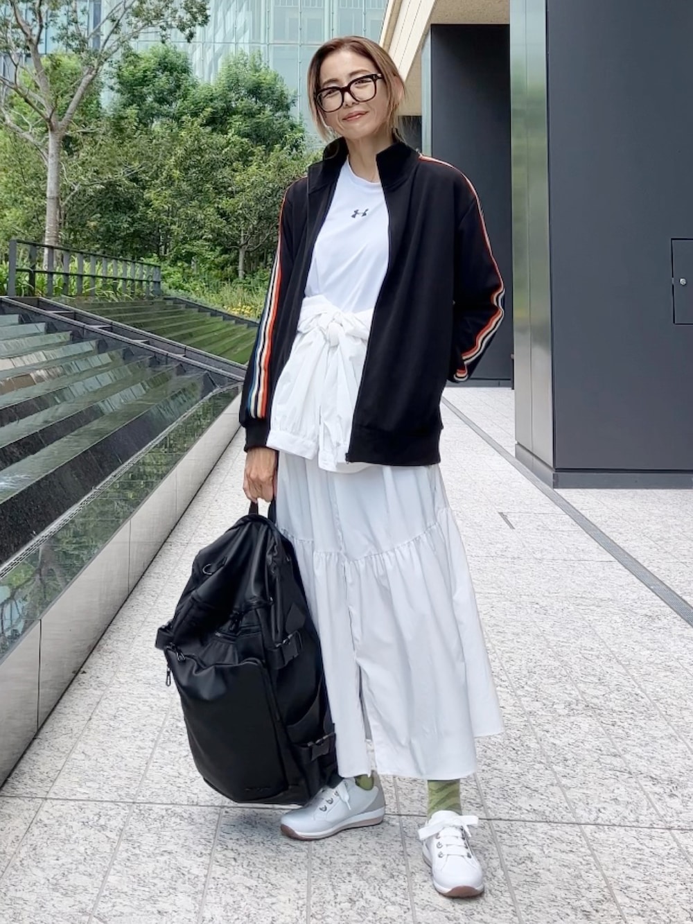 ブラック系のジャージ、ブラック系のバックパック/リュック、ホワイト系のスニーカーを着用したレディースの秋コーディネートの2枚目の写真