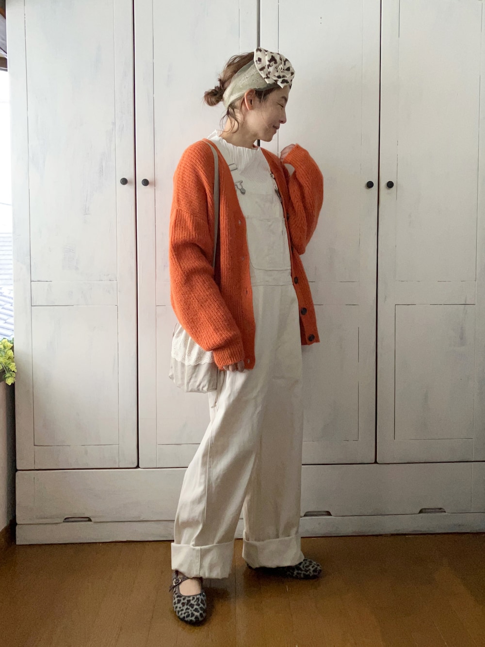 ホワイト系のサロペット/オーバーオール、ホワイト系のTシャツ/カットソー、オレンジ系のカーディガン/ボレロを着用したレディースの冬コーディネートの3枚目の写真