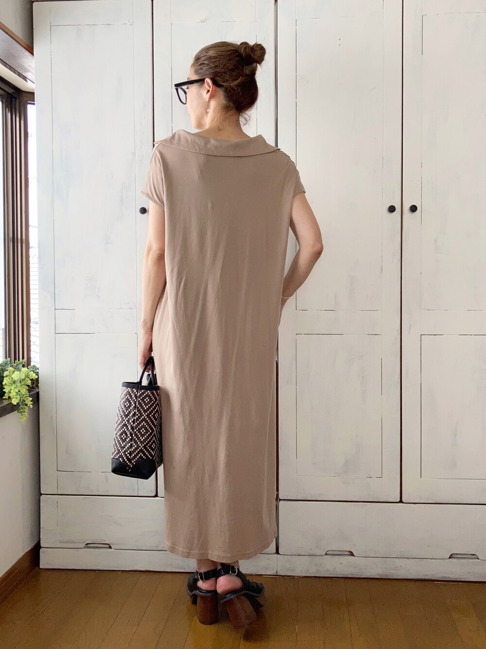 ベージュ系のワンピース、ブラック系のかごバッグ、ブラック系のサンダルを着用したレディースの夏コーディネートの2枚目の写真