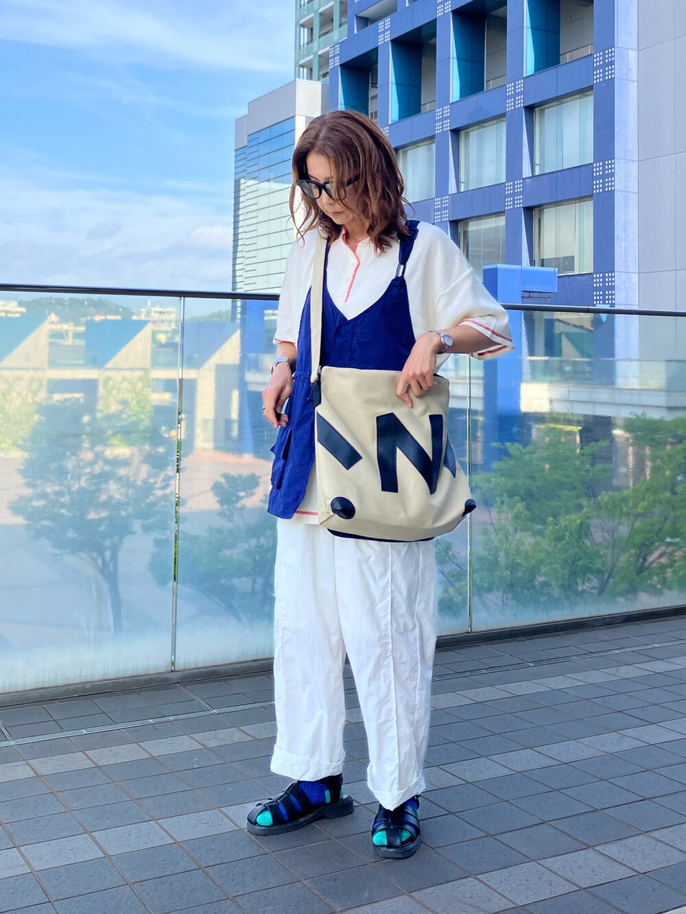 ブルー系のベスト、ベージュ系のトートバッグ、ホワイト系のTシャツ/カットソーを着用したレディースの夏コーディネートの2枚目の写真
