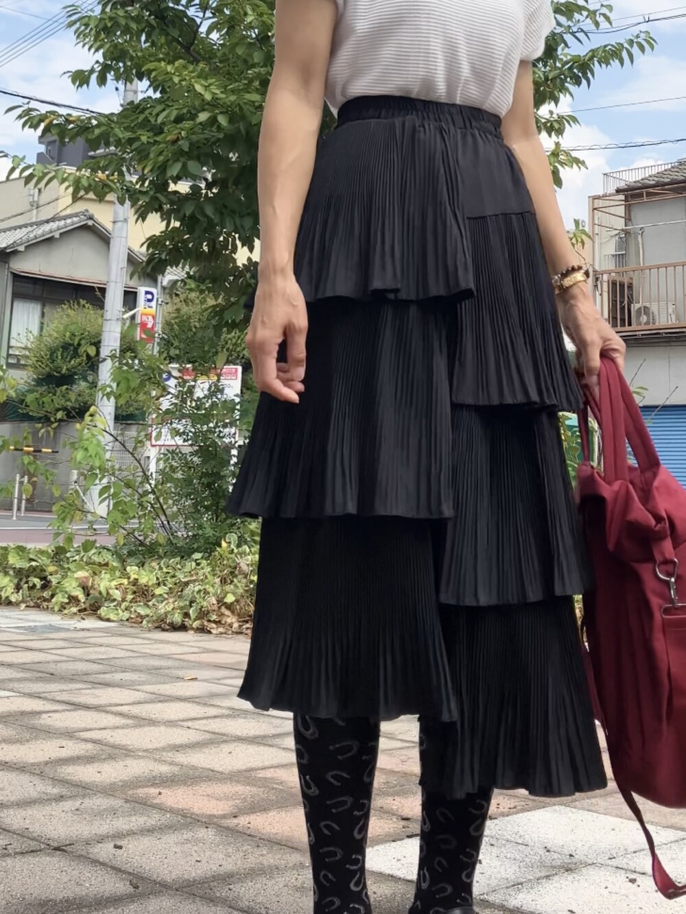 ブラック系のスカート、レッド系のボストンバッグ、ホワイト系のTシャツ/カットソーを着用したレディースの秋コーディネートの2枚目の写真