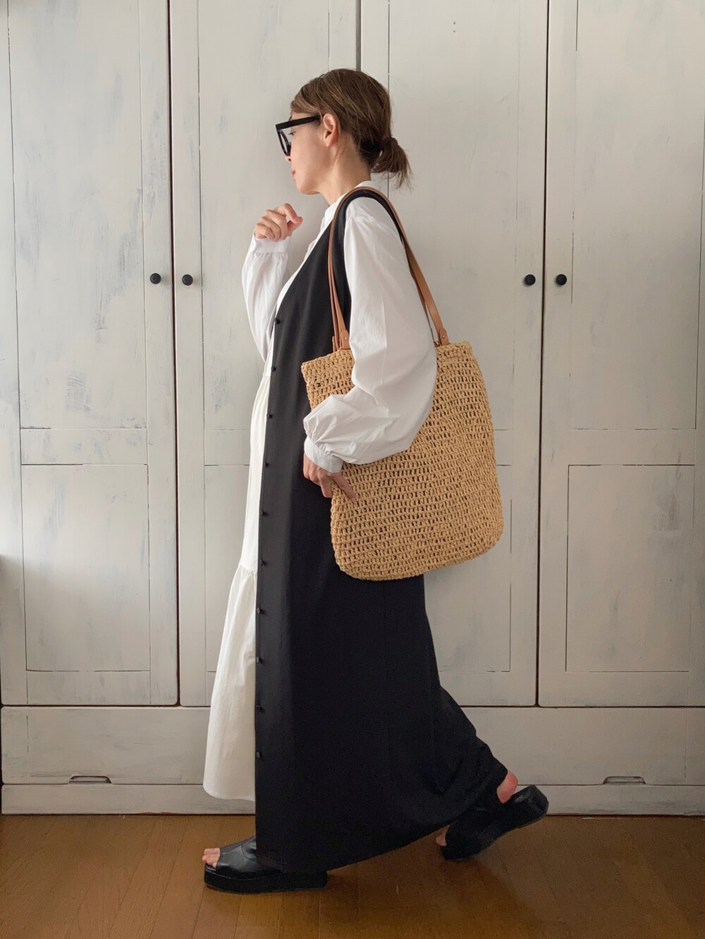 ブラック系のジャンパースカート、ホワイト系のワンピース/ドレス、ベージュ系のバッグを着用したレディースの春コーディネートの2枚目の写真