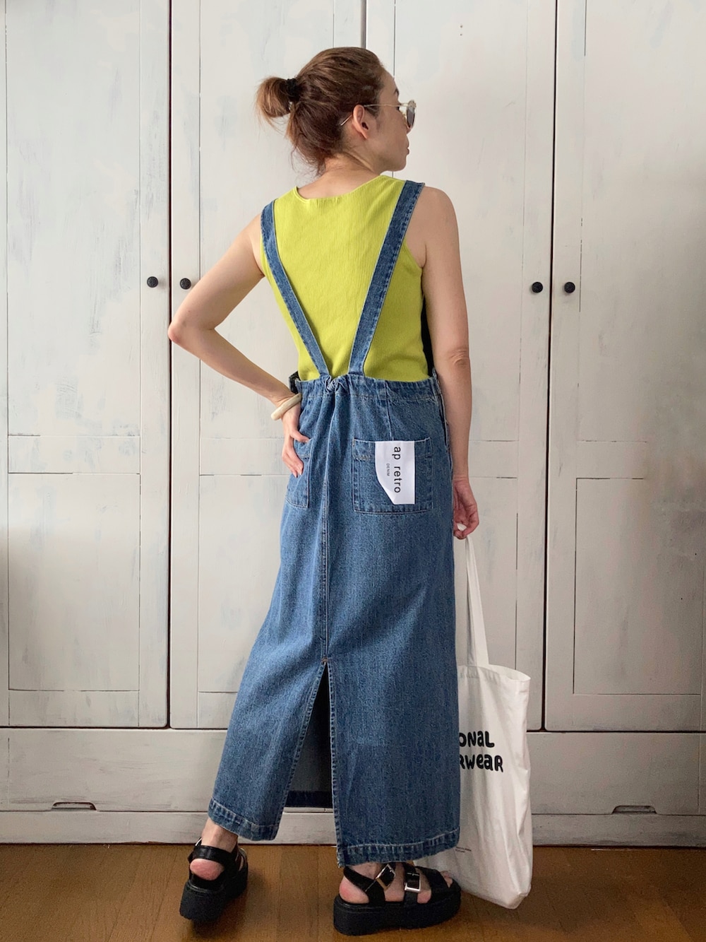 ブルー系のサロペット/オーバーオール、グリーン系のタンクトップ、ホワイト系のトートバッグを着用したレディースの夏コーディネートの3枚目の写真