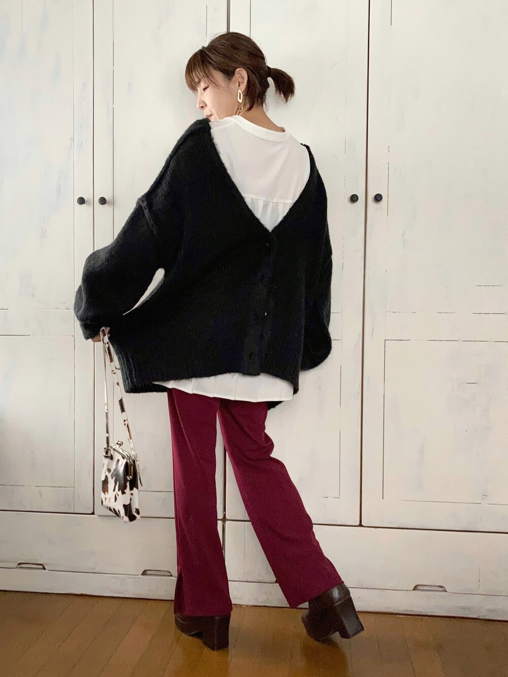 ブラック系のカーディガン/ボレロ、ホワイト系のシャツ/ブラウス、レッド系のスラックスを着用したレディースの冬コーディネートの2枚目の写真