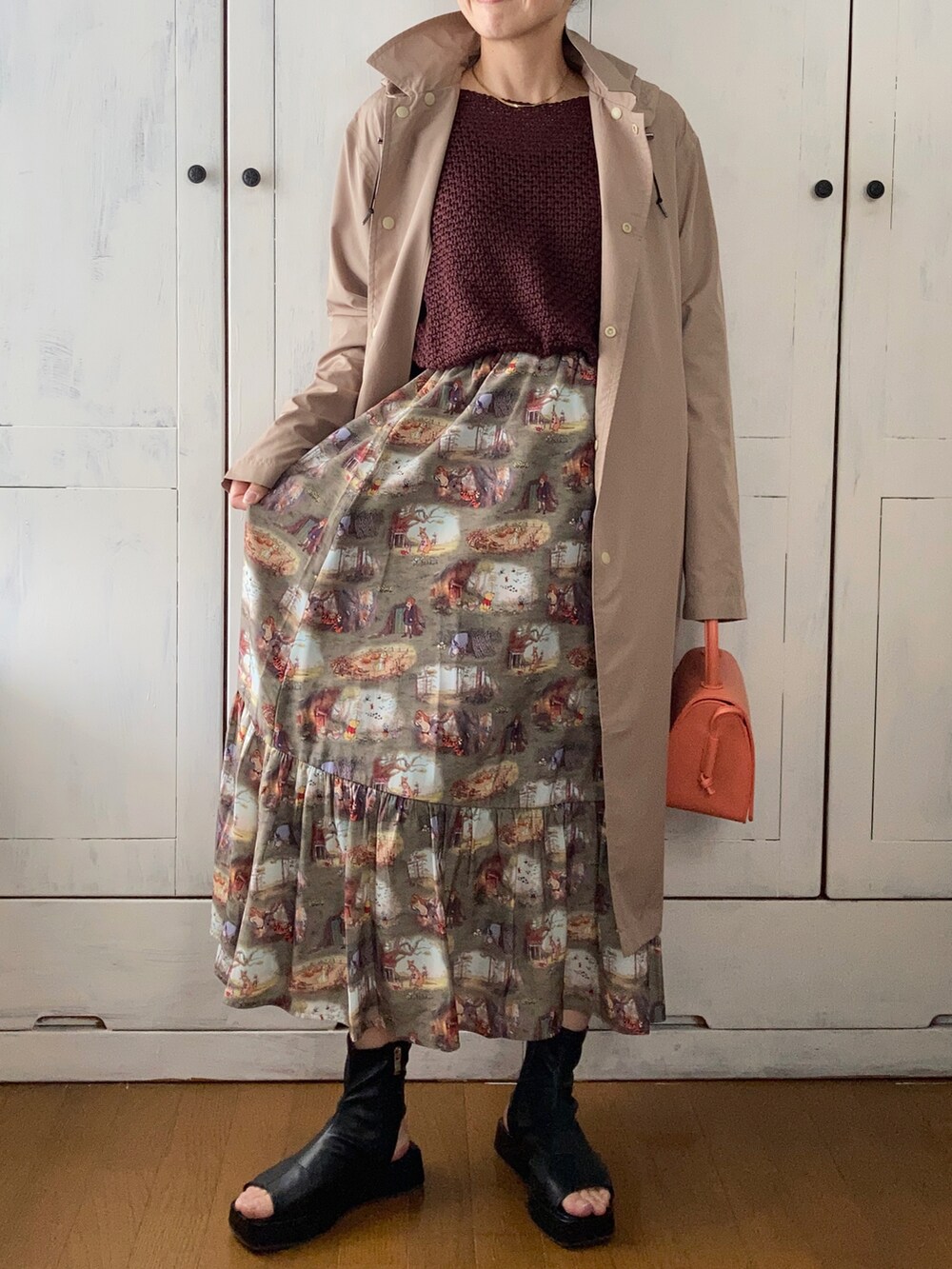 オレンジ系のショルダーバッグ、グリーン系のスカート、ブラック系のブーツを着用したレディースの春コーディネートの2枚目の写真