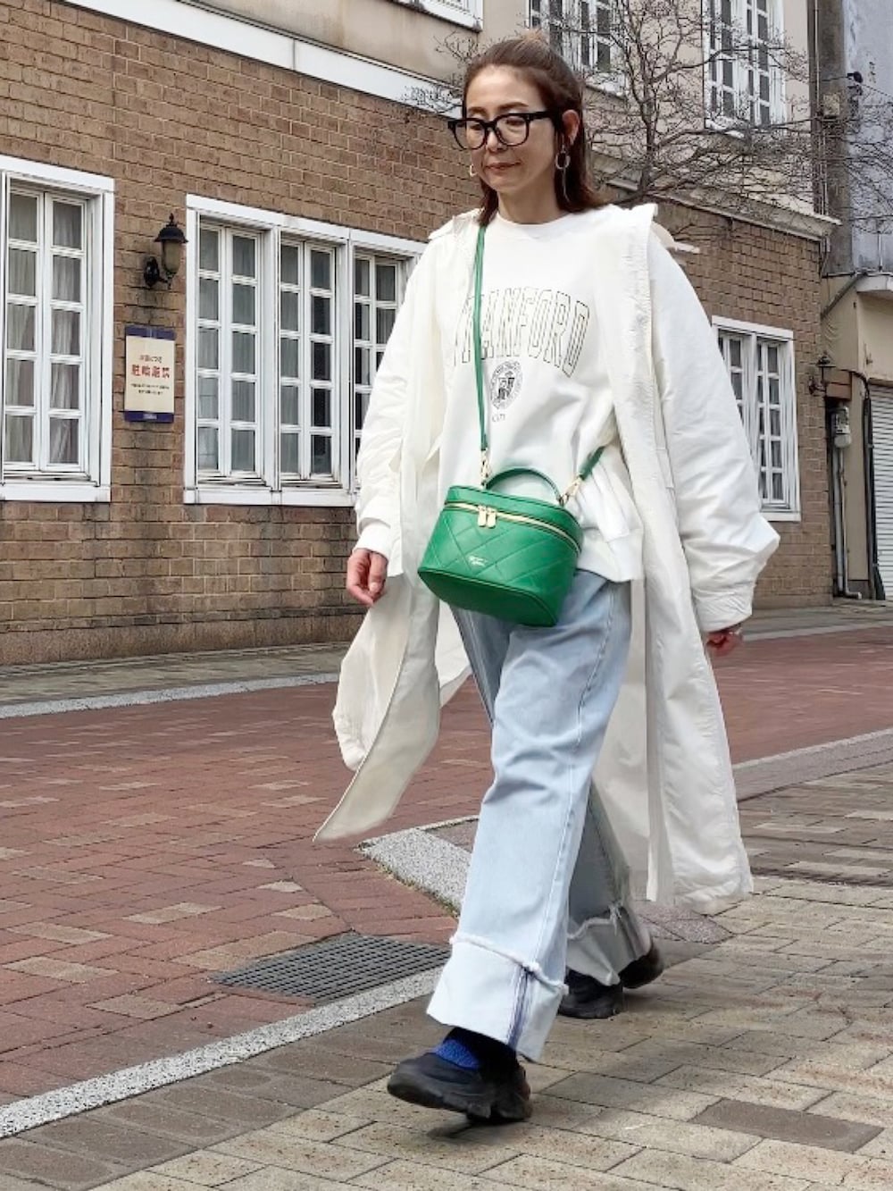 ホワイト系のスウェット、ブルー系のデニムパンツ、グリーン系のショルダーバッグを着用したレディースの春コーディネートの3枚目の写真